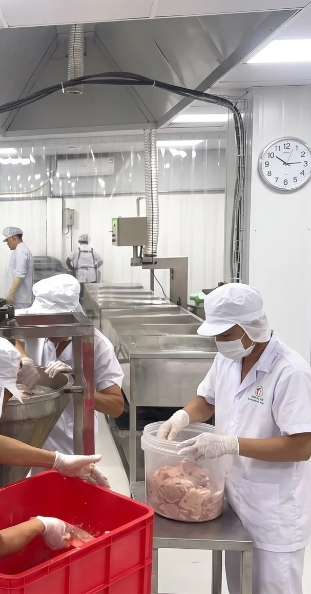 Công nhân mặc đồ bảo hộ trắng nhận thịt trong phòng sạch của xưởng Nem Luji ở Đông Anh