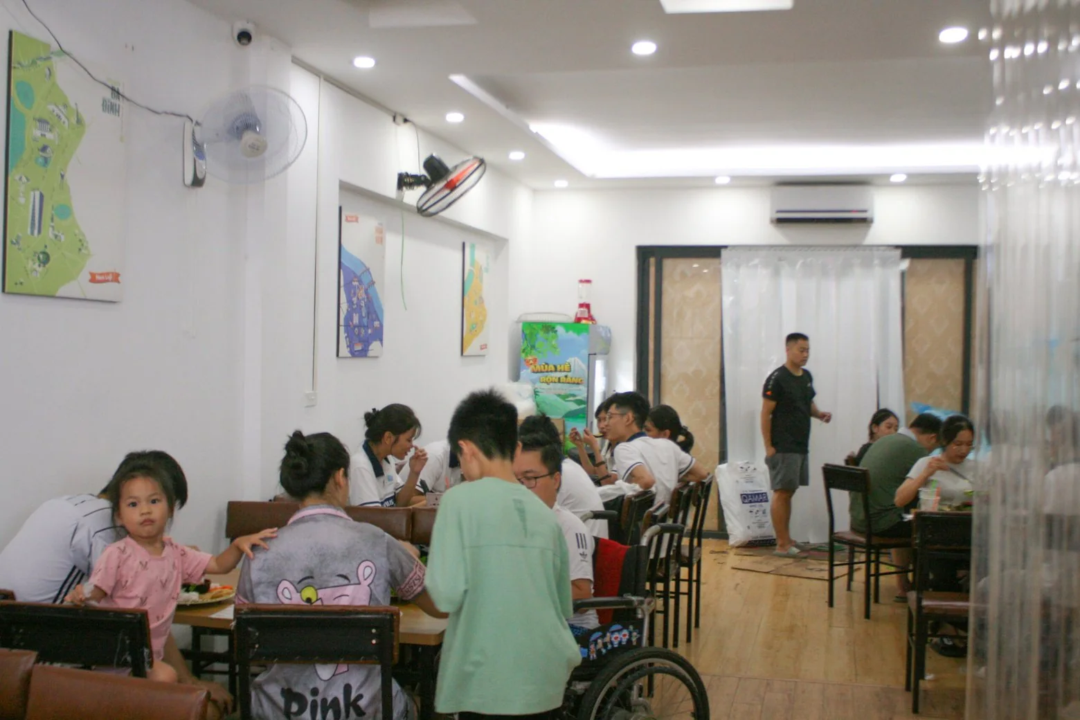 Gia đình có trẻ nhỏ ngồi ăn ở dãy bàn sát tường