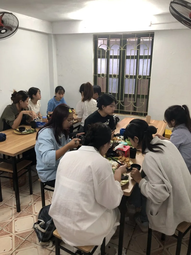 Nhóm bạn trẻ ngồi ăn quanh bàn gỗ